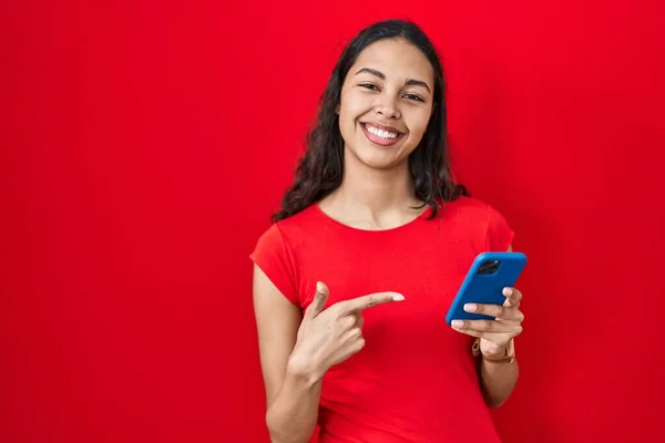 Young Brazilian Woman Using Smartphone Red Background Cheerful Smile Face —  Fotos de Stock