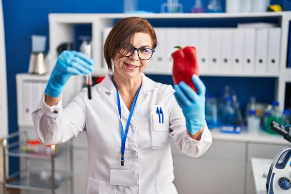 中年妇女科学家在实验室里拿着胡椒和血液试管 — 图库照片