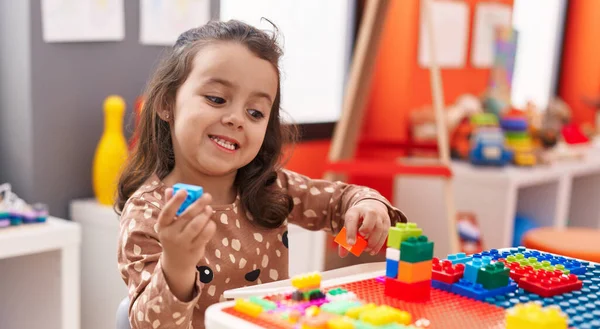 stock image Adorable hispanic girl playing with construction blocks sitting on table at kindergarten