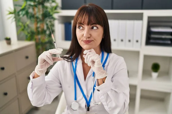 Young Brunette Doctor Woman Holding Syringe Serious Face Thinking Question — Photo