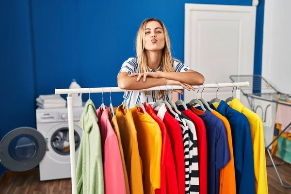 Young Blonde Woman Laundry Room Clean Clothes Looking Camera Blowing — Stockfoto