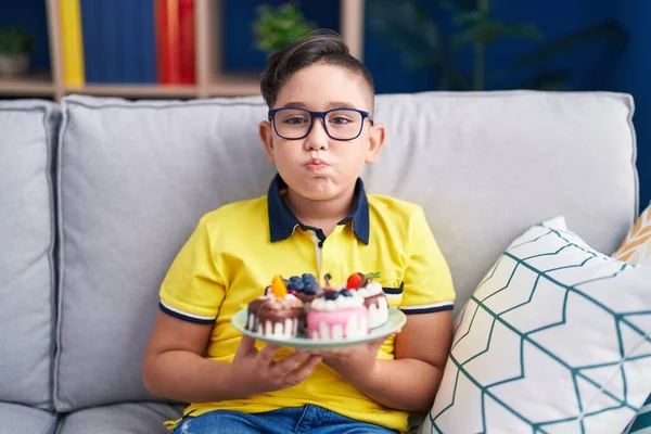 Young Hispanic Kid Holding Cake Sweets Puffing Cheeks Funny Face — Stock Photo, Image