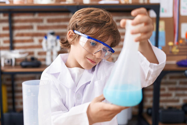 Adorable caucasian boy student holding test tube at classroom