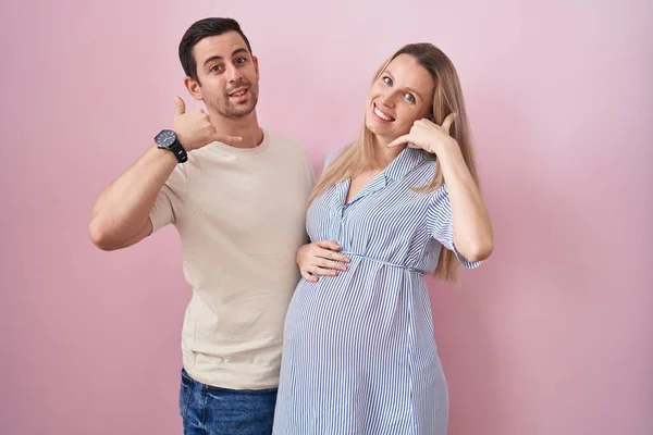 Casal Jovem Esperando Bebê Sobre Fundo Rosa Sorrindo Fazendo Gesto — Fotografia de Stock