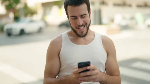 若いヒスパニック男笑顔自信を持って使用してスマートフォンでストリート — ストック写真