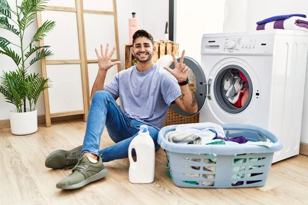 Young Hispanic Man Putting Dirty Laundry Washing Machine Showing Pointing — Stock Photo, Image