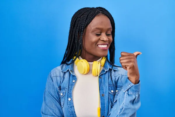 African Woman Braids Standing Blue Background Pointing Thumb Side Smiling — Photo