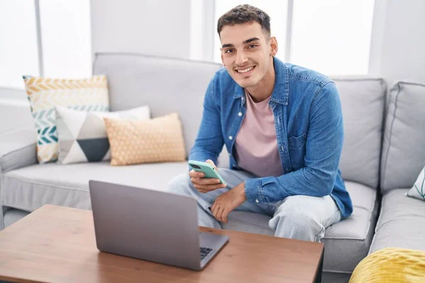 Joven Hombre Hispano Usando Laptop Smartphone Sentado Sofá Casa —  Fotos de Stock