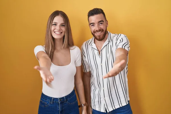 Young Couple Standing Yellow Background Smiling Cheerful Offering Palm Hand — 图库照片