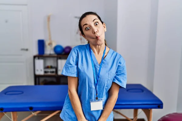 Mladá Hispánka Uniformě Fyzioterapeutky Která Stojí Klinice Dělá Rybí Ksicht — Stock fotografie