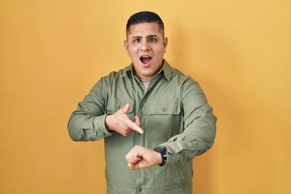Hispanic Young Man Standing Yellow Background Hurry Pointing Watch Time — стоковое фото