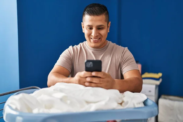 Ung Latin Man Med Smartphone Hängande Kläder Klädstreck Tvättstuga — Stockfoto