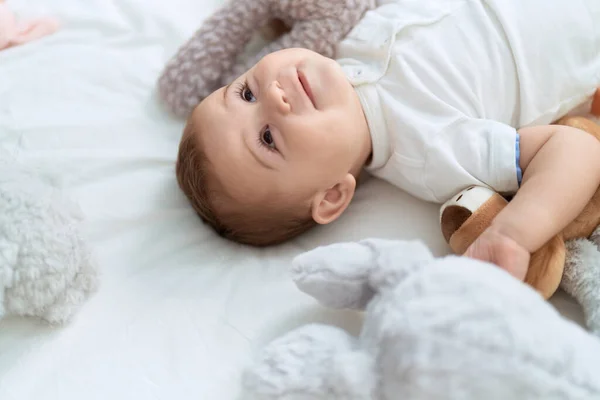 Очаровательный Малыш Уверенно Улыбающийся Лежа Кровати Куклами Спальне — стоковое фото