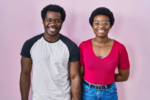 年轻的非洲裔美国夫妇站在粉红的背景上 脸上挂着快乐而凉爽的笑容 幸运的人 — 图库照片