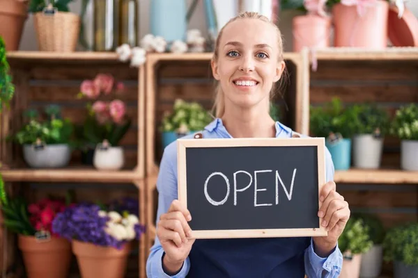 Young caucasian woman working at florist holding open sign smiling with a happy and cool smile on face. showing teeth.