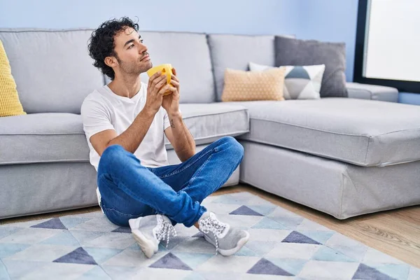 Genç İspanyol adam evde oturmuş kahve içiyor.
