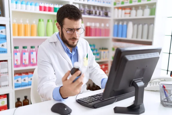 Young Hispanic Man Pharmacist Using Computer Holding Medication Bottle Pharmacy — Stock Photo, Image