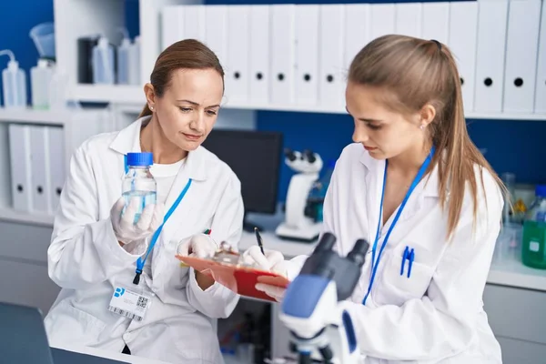Δύο Γυναίκες Επιστήμονες Γράφουν Έγγραφα Μέτρησης Υγρών Στο Εργαστήριο — Φωτογραφία Αρχείου