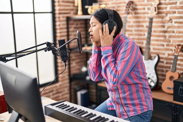 Young chinese woman artist singing song at music studio