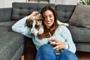 Young woman hugging dog drinking mate infusion at home