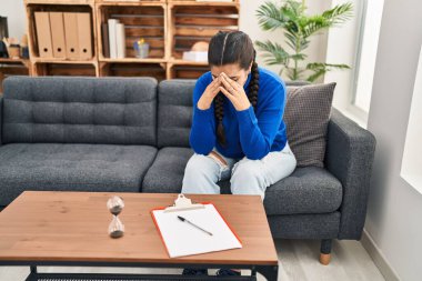 Young hispanic woman crying having psychology session at clinic