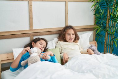 Two kids waking up stretching arms at bedroom