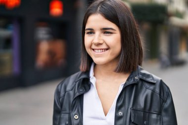 Young beautiful hispanic woman smiling confident looking to the side at street