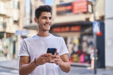 Sokakta akıllı telefon kullanan, kendine güvenen genç bir İspanyol.