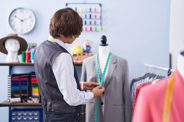 Young blond man tailor measuring jacket at clothing factory