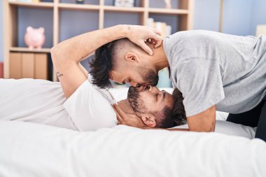 Young couple hugging each other and kissing lying on bed at bedrooom