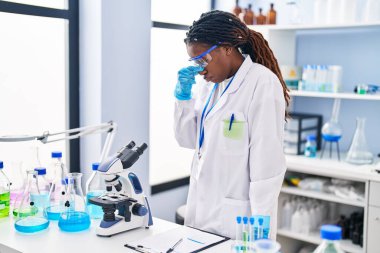 African american woman scientist stressed standing at laboratory