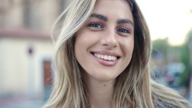 Sokakta kendine güvenen genç sarışın kadın gülümsüyor