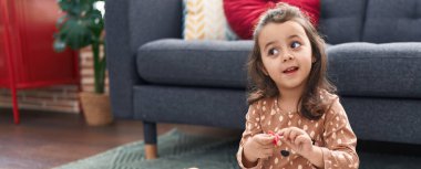 Adorable hispanic girl smiling confident sitting on floor at home