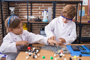 Erkek ve kız kardeş öğrenciler laboratuvar sınıfında deney yapıyorlar.