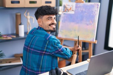 Genç İspanyol ressam, resim stüdyosunda kendine güvenen gülümsüyor.