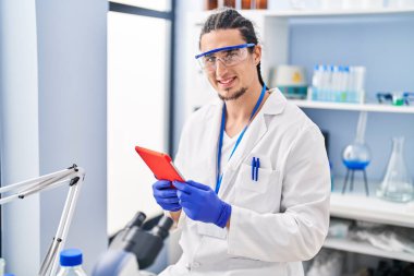 Young man wearing scientist uniform using touchpad at laboratory