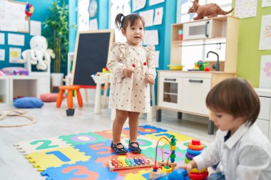 Two kids playing xylophone standing at kindergarten