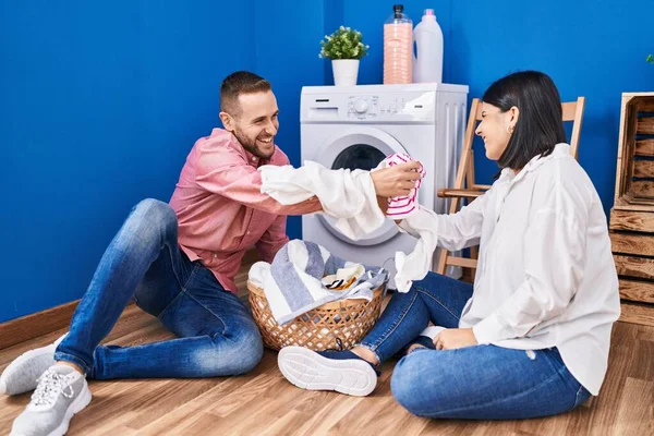洗濯室で男と女の夫婦が服と戦う — ストック写真