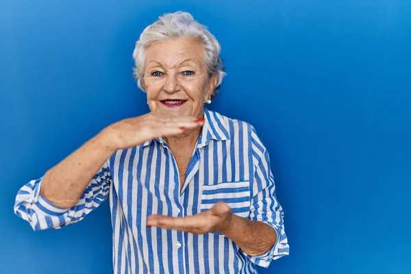 Starsza Kobieta Siwymi Włosami Stojąca Nad Niebieskim Tłem Gestykulująca Dłońmi — Zdjęcie stockowe