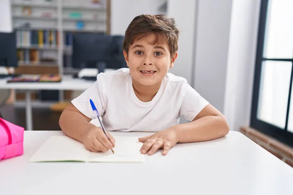 可敬的惊慌失措的男孩微笑着在课堂上信心十足地写着 — 图库照片