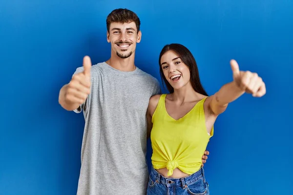Young Hispanic Couple Standing Together Blue Background Approving Doing Positive — Stockfoto