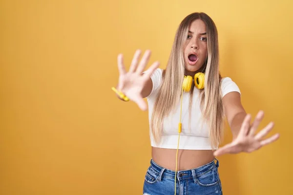 Young Blonde Woman Standing Yellow Background Wearing Headphones Afraid Terrified — Stock Photo, Image