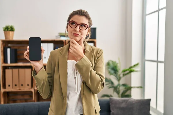 Young Woman Working Consultation Office Holding Smartphone Serious Face Thinking — Stock Photo, Image
