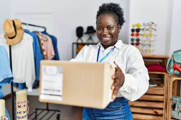 Young African American Woman Shopkeeper Smiling Confident Holding Package Clothing — Stockfoto