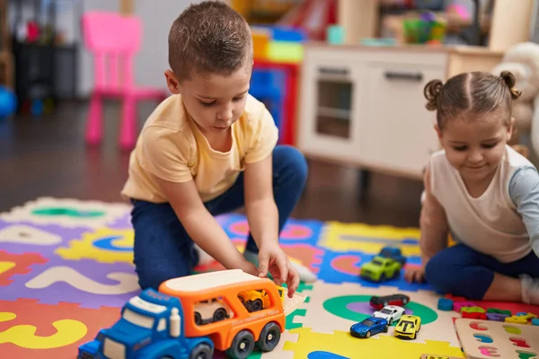 유치원 바닥에 앉아서 자동차 장난감 게임을 — 스톡 사진