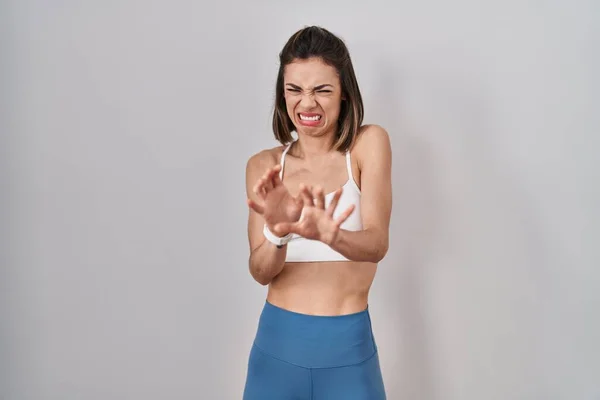 Hispanic woman wearing sportswear over isolated background disgusted expression, displeased and fearful doing disgust face because aversion reaction.