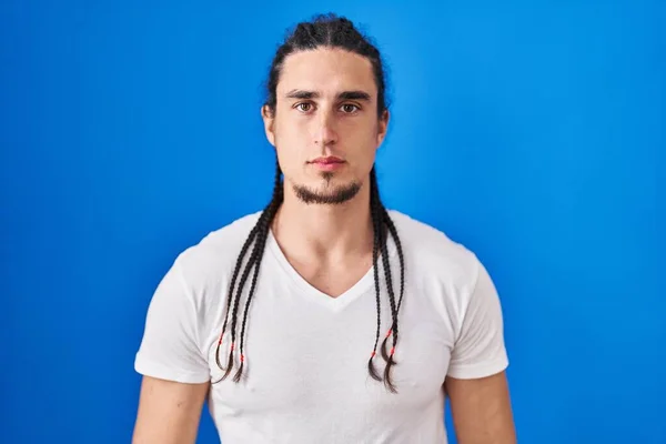Hispanic Man Long Hair Standing Blue Background Relaxed Serious Expression — Stockfoto
