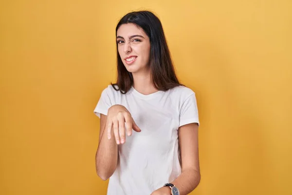 Young beautiful woman standing over yellow background disgusted expression, displeased and fearful doing disgust face because aversion reaction.