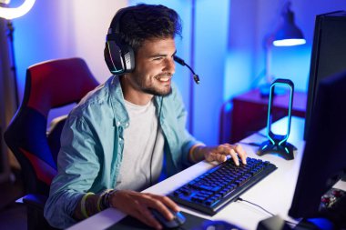 Oyun odasında bilgisayar kullanarak video oyunu oynayan İspanyol asıllı genç adam.