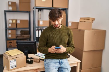 Young arab man ecommerce business worker using smartphone at office